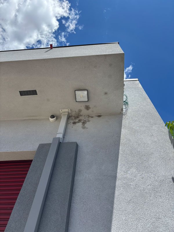 Commercial building wall with dark staining below the light fixture before washing